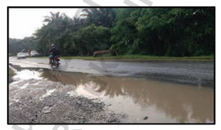 Jalan berlubang yang ditutupi air